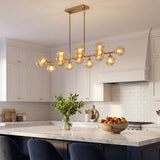 Gold amber glass globe linear chandelier above marble white cabinet kitchen island
