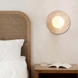 Japandi style travertine wall sconce with glass globe in bedroom