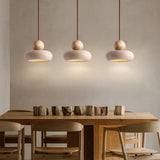 hree travertine pendant lights above wooden dining table, wabi sabi style