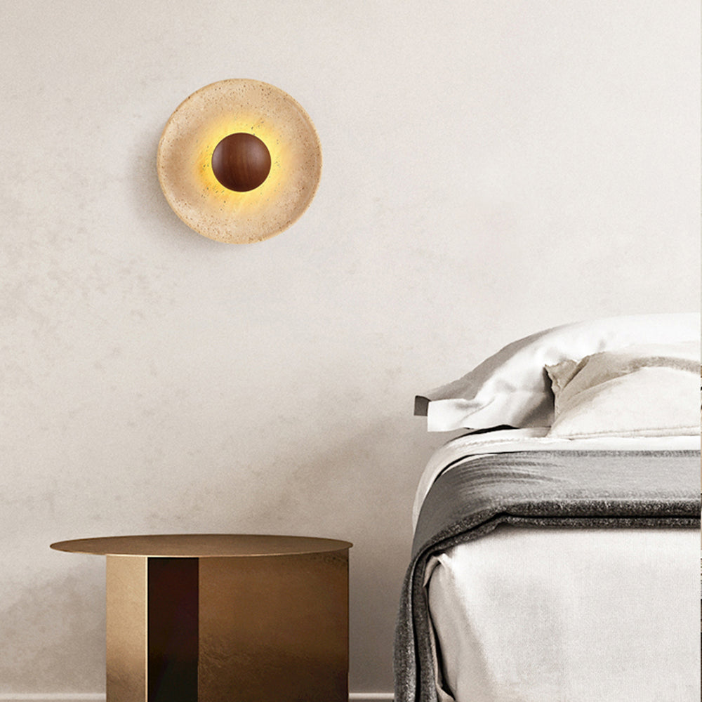 Minimalist travertine wall sconce beside bed with warm glow