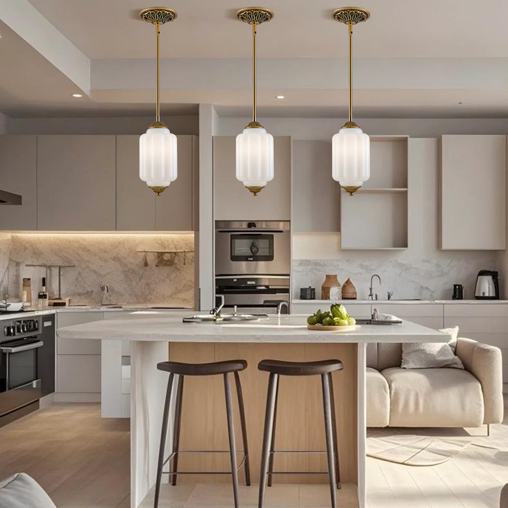 Three antique brass mini glass pendant lights above marble kitchen island counter